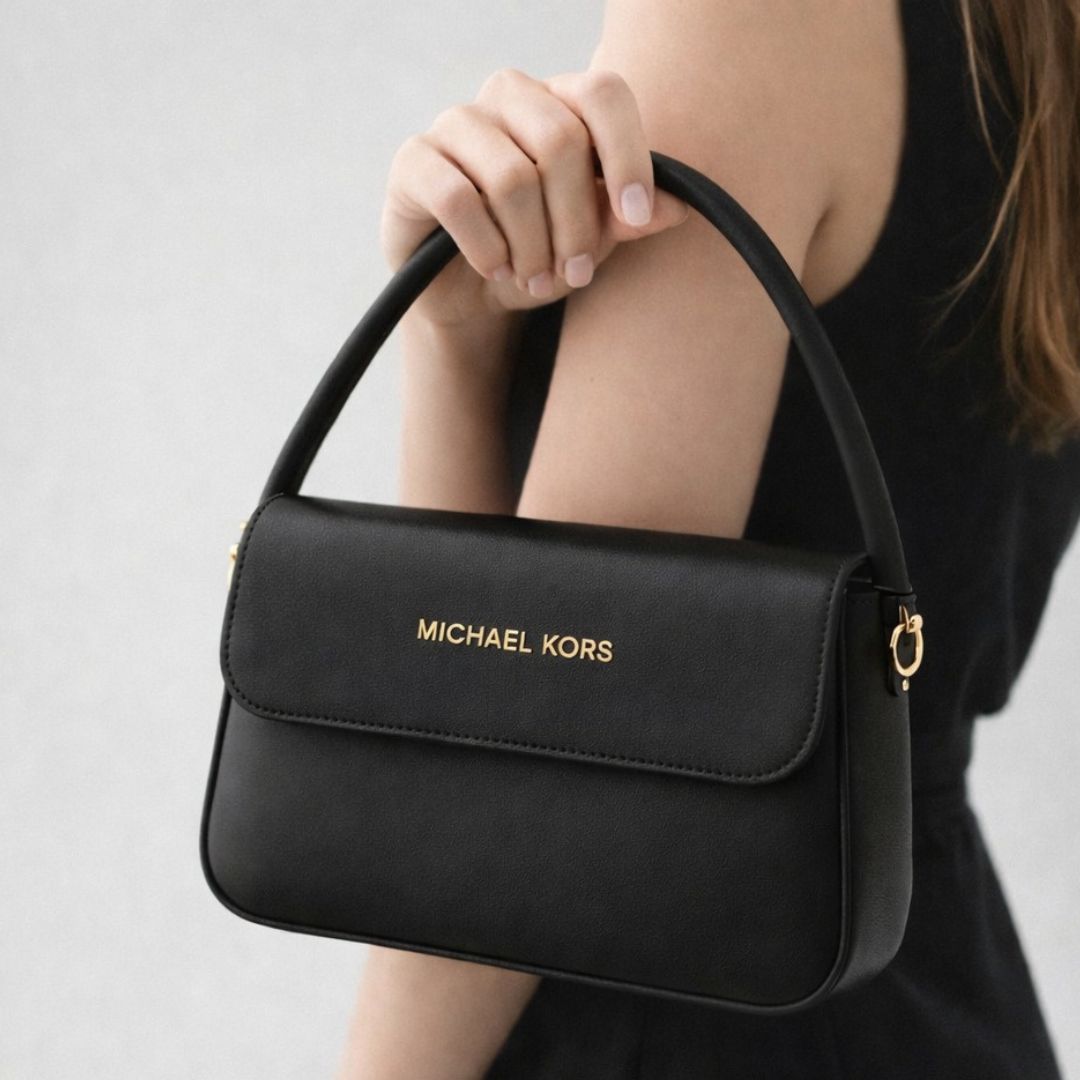 حقيبة مايكل كورس الجلدية مزينة بشعار معدني مذهب ومقبض علوي مقوس 